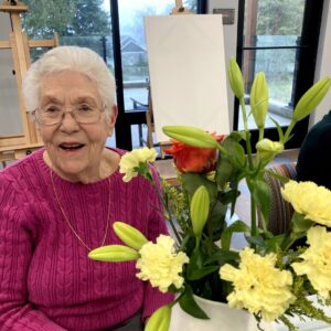 Mary, Fieldstone of Bainbridge resident, sitting with flowers.