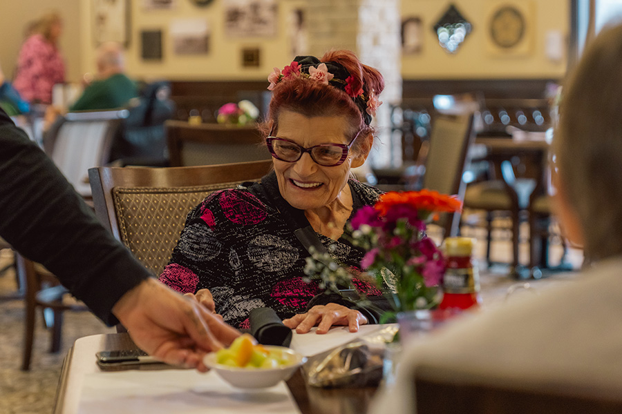 Older woman smiling while being served lunch at Fieldstone Village at Keizer Ridge in Keizer, Oregon.
