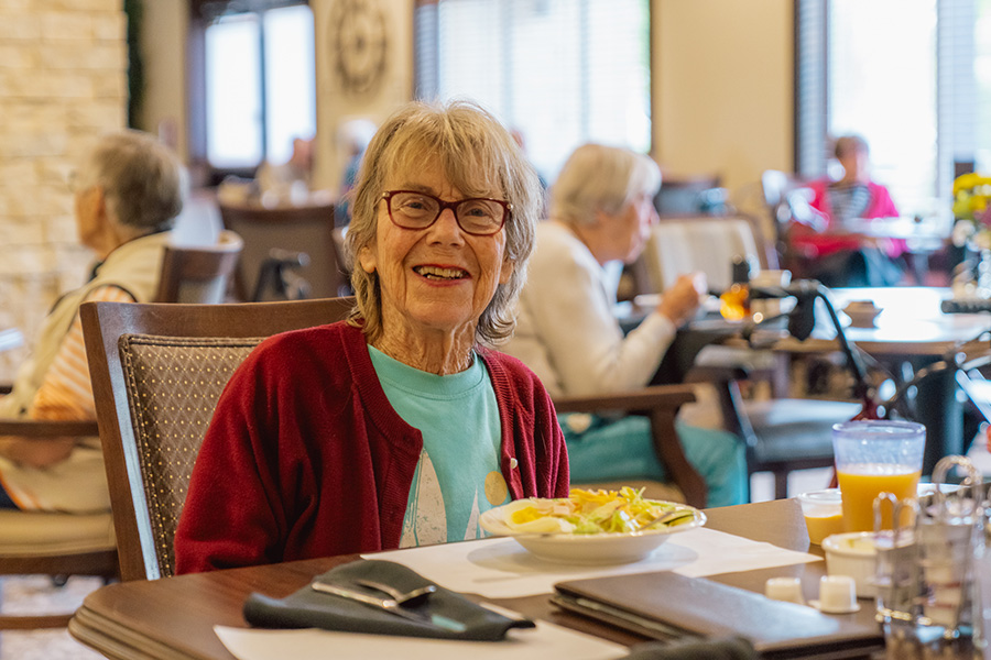 Smiling older woman eating lunch at Fieldstone Village at Keizer Ridge, an assisted living and memory care community in Keizer, Oregon.