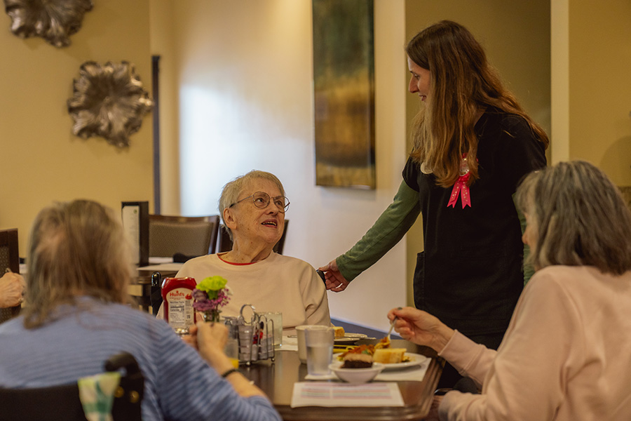 female staff member chatting with residents while eating lunch