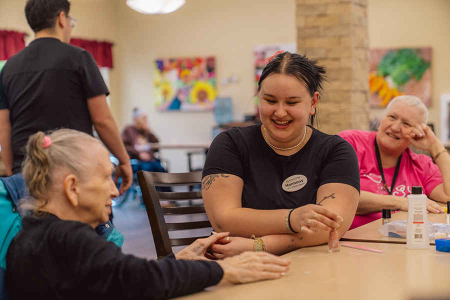 Female staff member of Fieldstone Village at Keizer Ridge talking and laughing with one of the residents.