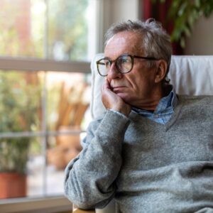 An older man looks out a window.