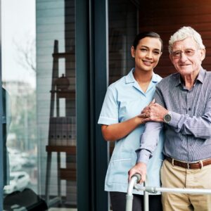 An older man stands with his caregiver.