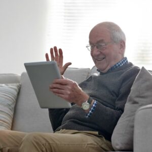 An older man uses a tablet to stay connected with family.