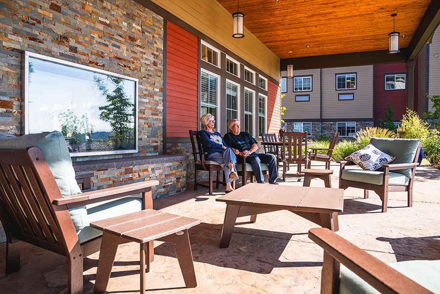 Two people relax on a patio with comfortable furniture.