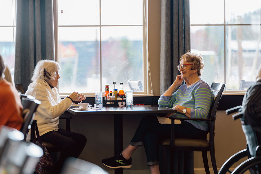 Two elderly women enjoying a conversation at a café.