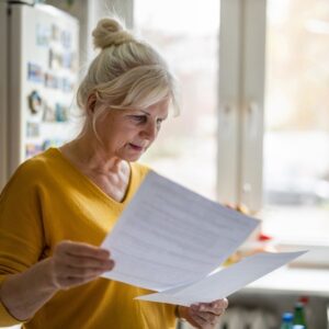An older woman looks through paperwork on senior living costs.