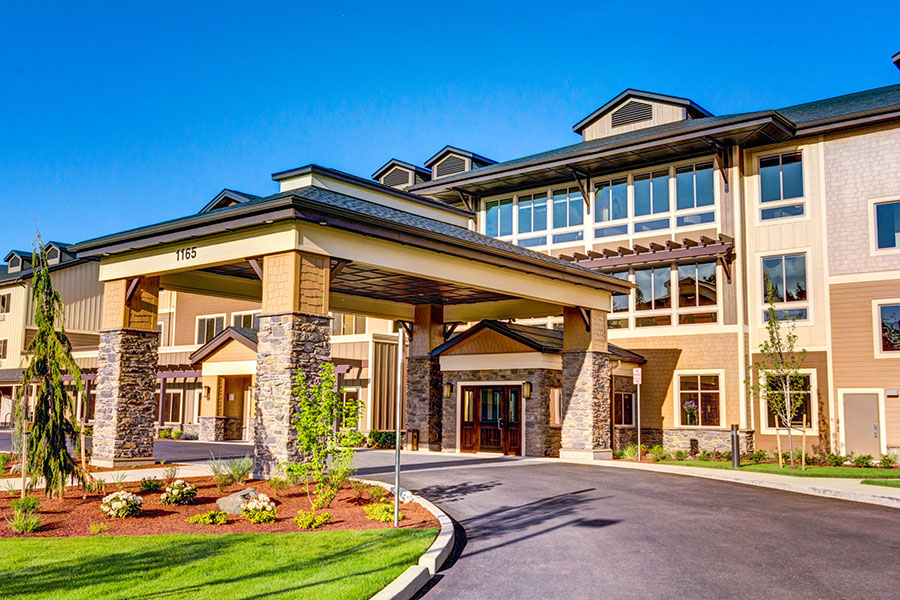 Modern building entrance with landscaped surroundings under clear blue sky.