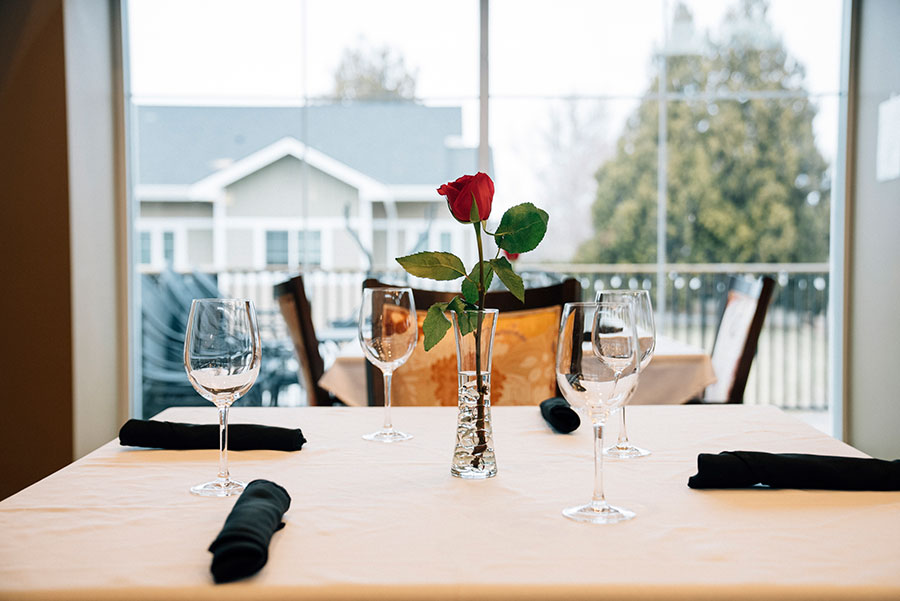 Elegant dining table with a rose centerpiece and glasses.