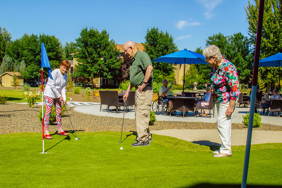 Seniors enjoying miniature golf outdoors on a sunny day.