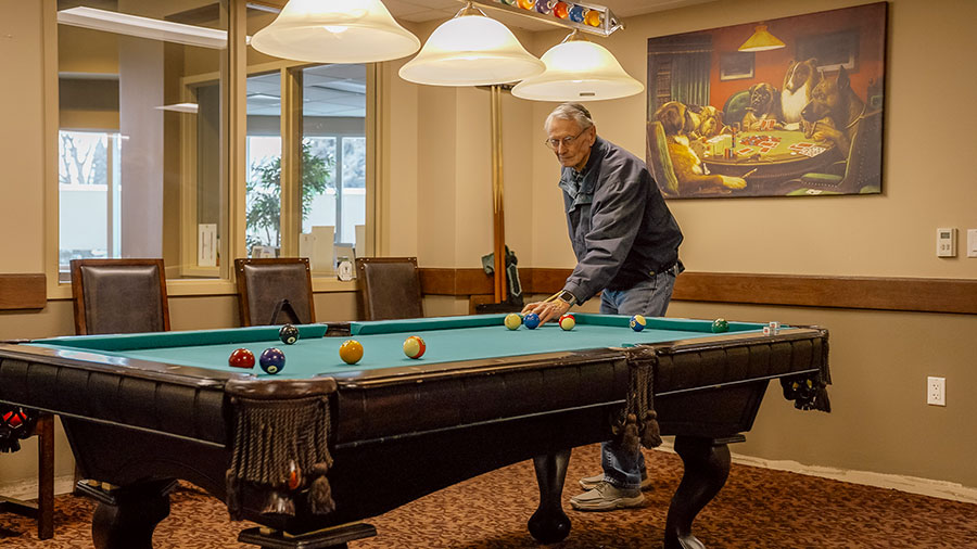 Man playing billiards in a cozy room with artwork.